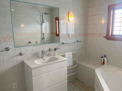 Merivale four bedroom house في كرايستشيرش: حمام مع حوض ومرآة وحوض استحمام