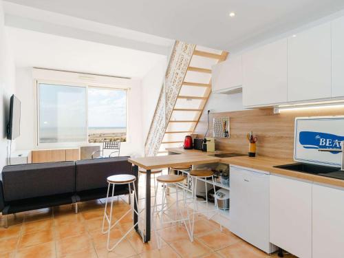 une cuisine avec des armoires blanches et une table avec des tabourets dans l'établissement Gruissan: Studio Mezzanine proche plage, animaux et parking - FR-1-409-168, à Gruissan