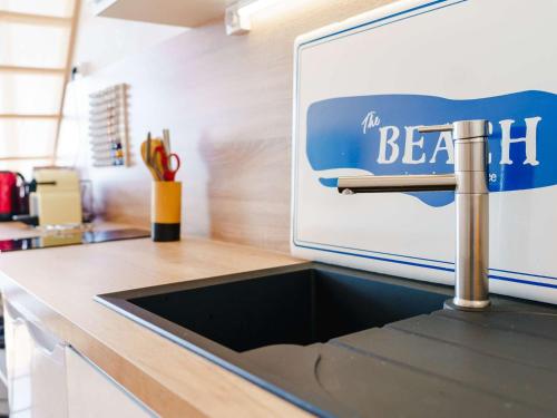 un évier de cuisine avec un panneau sur le mur au-dessus dans l'établissement Gruissan: Studio Mezzanine proche plage, animaux et parking - FR-1-409-168, à Gruissan