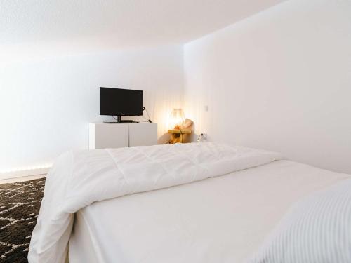 une chambre blanche avec un lit et une télévision dans l'établissement Gruissan: Studio Mezzanine proche plage, animaux et parking - FR-1-409-168, à Gruissan