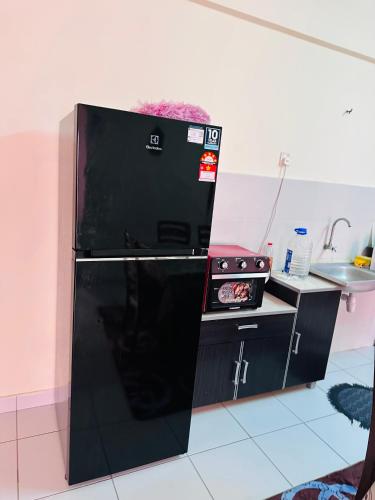 a black refrigerator in a kitchen with a stove at Tom’s Homestay in Batu Caves