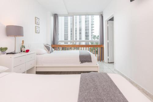 a white bedroom with a bed and a window at Girasole Suites in Miami Beach