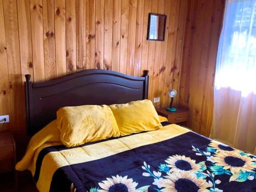 - une chambre avec un lit et un mur en bois dans l'établissement Cabañas El Colibrí, à Algarrobo