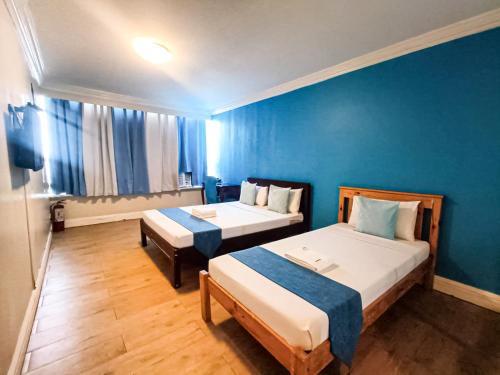 a room with two beds and a blue wall at Manila Airport Hotel by Urban Connect in Manila