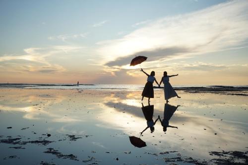 two women walking on the beach with an umbrella at KAMENOI HOTEL Kii-Tanabe in Tanabe