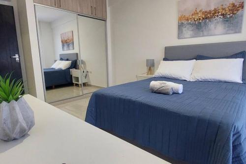 1 dormitorio con cama azul y espejo en Lujoso Dpto. en zona privilegiada. Amá Santa Cruz!, en Santa Cruz de la Sierra