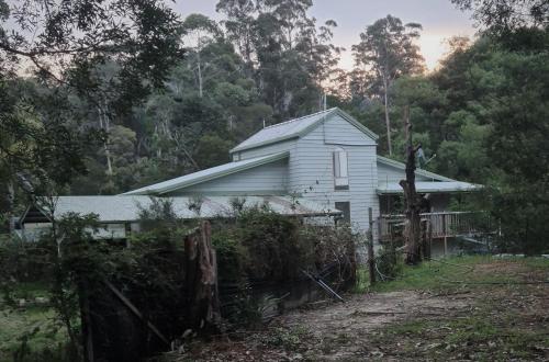 een wit huis met een hek ervoor bij Bird Songs Getaway Accommodation in Cabbage Tree Creek