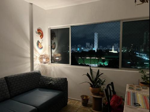 ein Wohnzimmer mit einem Sofa und Stadtblick in der Unterkunft Suite aconchegante na Torre in Recife