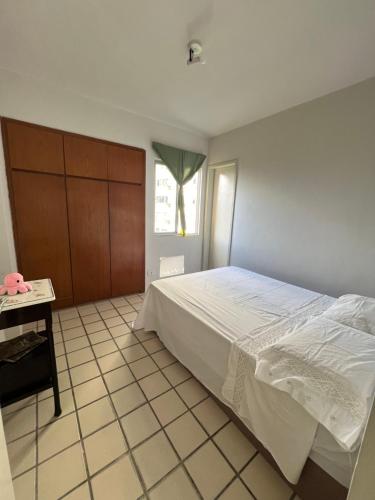 a bedroom with a large white bed and a table at Suite aconchegante na Torre in Recife
