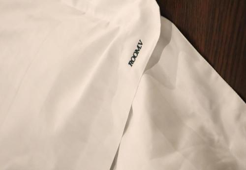 a white dress shirt with a blue logo on it at Room V by SECOM Jalan Megat in Batu Pahat