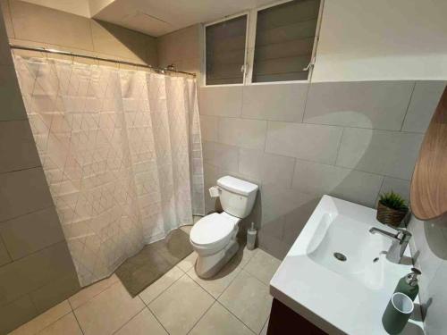 a bathroom with a toilet and a sink at 3 bd by airport El yunque Walk to the beach in San Juan