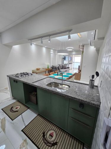 a kitchen with a green counter top and a living room at Lamore in Praia Grande
