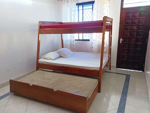 ein Etagenbett aus Holz in einem Zimmer mit einer Tür in der Unterkunft Mombasa , Kenya 2 bedroom Master Ensuite in Mombasa