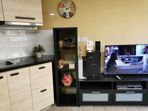 a kitchen with a television and a clock on the wall at Elegant & Trendy Apt in a Peaceful Area in Limassol