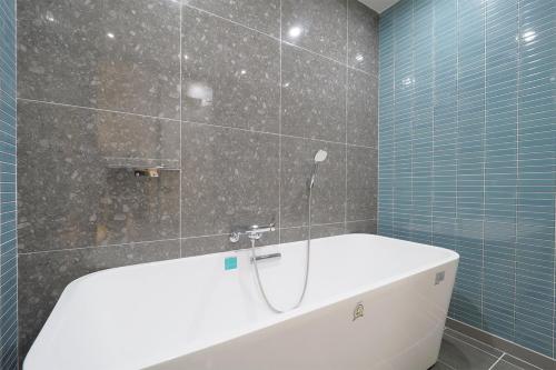 a bath tub in a bathroom with blue tiles at HOTEL YUNA Business in Busan