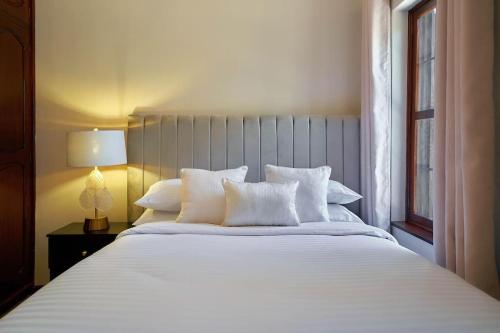 uma cama branca com almofadas brancas e uma janela em Olive Home Arusha em Nasulo