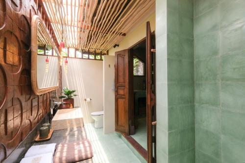 a bathroom with a toilet and a wooden ceiling at Rumah Senang - Walk to Beach in Balian