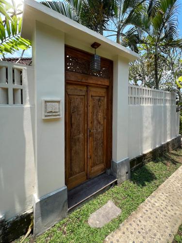 a small white house with a wooden door at Rumah Senang - Walk to Beach in Balian