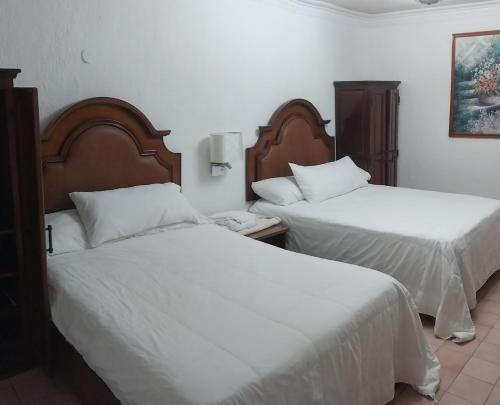 two beds in a hotel room with white sheets at Hermosa casa cuatro recámaras independientes CA in Mérida