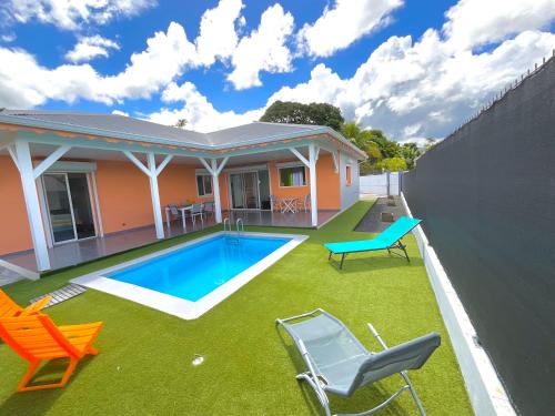 une arrière-cour avec une piscine, des chaises et une maison dans l'établissement Évasion tropicale Villa de rêve avec piscine à Petit Bourg, à Petit-Bourg