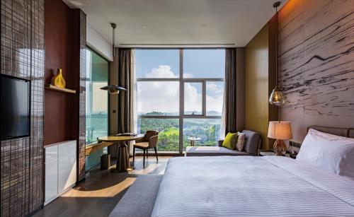a hotel room with a bed and a large window at Wanda Realm Heshan in Jiangmen