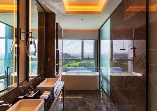 a bathroom with two sinks and a tub and a window at Wanda Realm Heshan in Jiangmen