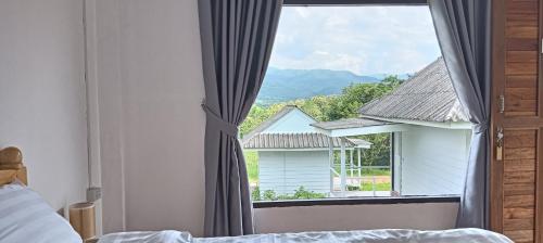 a bedroom with a bed and a window with a view at Pai sunrise camping resort in Pai