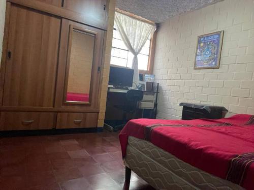 a bedroom with a bed and a desk and a window at comfortable and spacious house with garage in Amatitlán