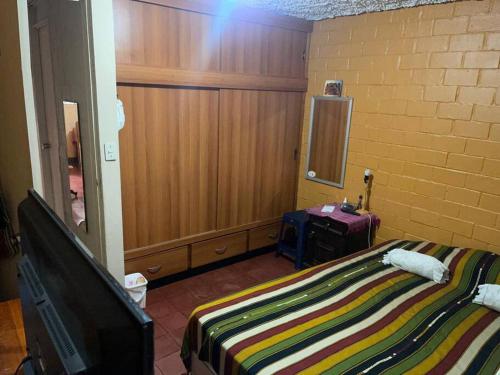 a bedroom with a bed and a tv and a wall at comfortable and spacious house with garage in Amatitlán
