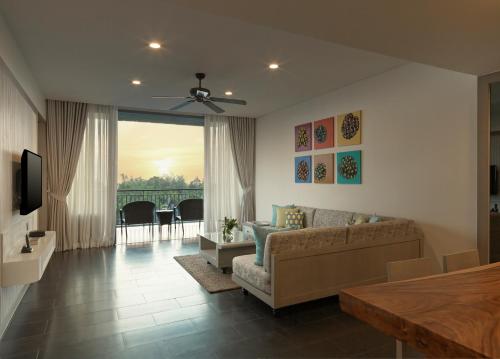 a living room with a couch and a television at Avani Plus Mai Khao Phuket Suites in Mai Khao Beach