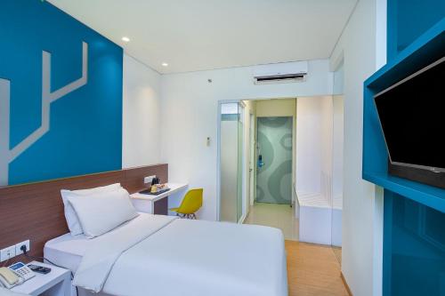 a hotel room with a bed and a tv at 1O1 URBAN Jakarta Pemuda in Jakarta