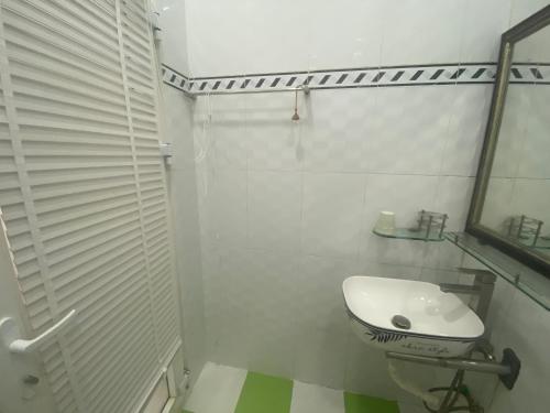 Baño blanco con lavabo y espejo en Villa homestay Misa, en Phan Thiet