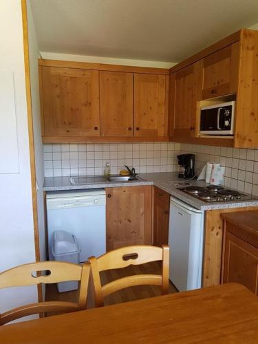 a kitchen with wooden cabinets and a table and chairs at LES PETITS ETERLOUS Appartement T3 36m2 à Puy St Vincent 1800 Alpes du sud 6 personnes parking privé couvert in Puy-Saint-Vincent