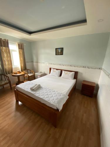 um quarto com uma cama com lençóis brancos e pisos em madeira em Thanh Bình 2 Hotel em Ho Chi Minh