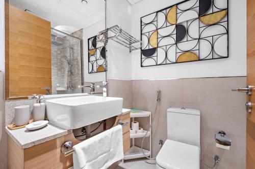 a bathroom with a sink and a toilet and a mirror at Perfect Getaway Studio APT Aura by Aziza in Dubai