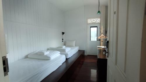 two beds in a white room with a window at Lana Beds & Space in Chiang Mai