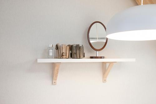 a white shelf with a mirror on a wall at Jeju Aria Pension in Jeju