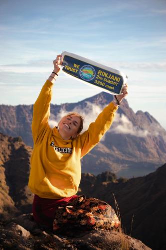 a woman holding up a board on top of a mountain at Tastura Homestay in Praya