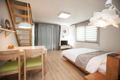 una camera con letto, scrivania e tavolo di Jeju Aria Pension a Jeju