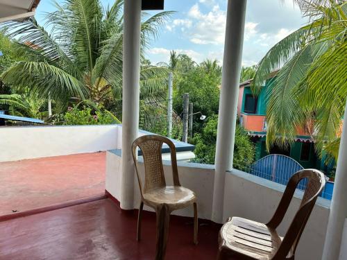 two chairs sitting on a balcony with palm trees at TPK Trinco Holiday Inn in Trincomalee