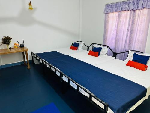 a bedroom with two beds with blue and red pillows at TPK Trinco Holiday Inn in Trincomalee