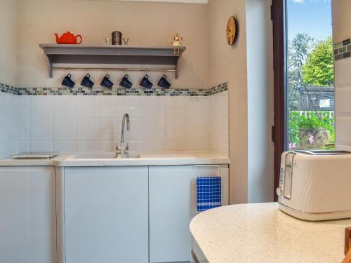 a kitchen with white cabinets and a sink at Havre De Calme in Halstead