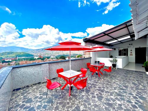 um pátio com cadeiras vermelhas, mesas e guarda-sóis em Edificio Victory Medellin - Apartamentos Acogedores y Equipados 100MB Wi-Fi, Central & Terraza Compartida em Medellín