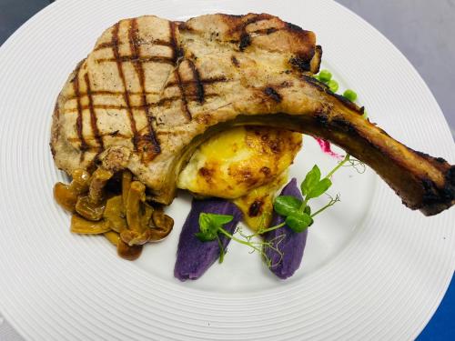a white plate with a piece of meat and vegetables at Hotel Dobru in Slănic-Moldova