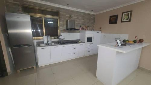 cocina con armarios blancos y nevera de acero inoxidable en Heritage Accommodation, en Kigali