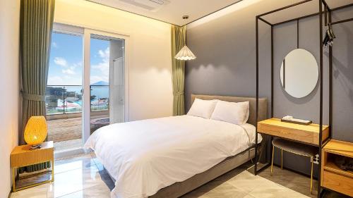 1 dormitorio con cama con espejo y ventana en Ganghwa Elijah Resort en Incheon