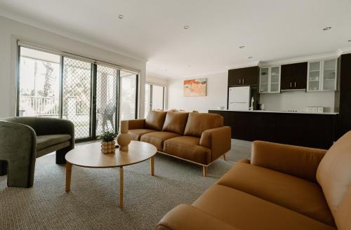 ein Wohnzimmer mit Sofas und einem Tisch sowie eine Küche in der Unterkunft Yarrawonga Waterfront Apartments in Mulwala