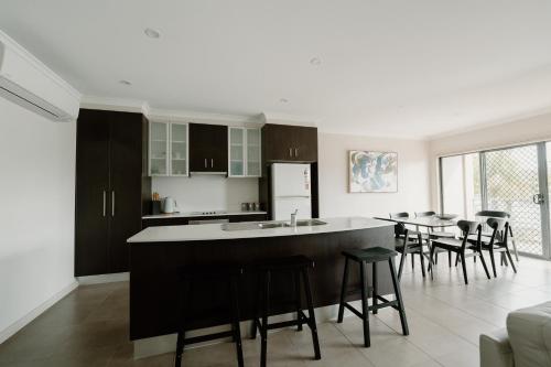 a kitchen with black cabinets and a kitchen island with bar stools at Yarrawonga Waterfront Apartments in Mulwala