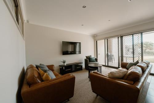 a living room with two couches and a tv at Yarrawonga Waterfront Apartments in Mulwala