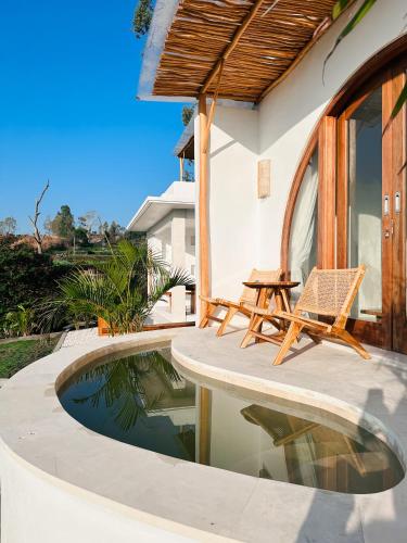 a patio with a table and a chair next to a pool at Garden Hill Kintamani with Natural Hot Springs in Kubupenlokan